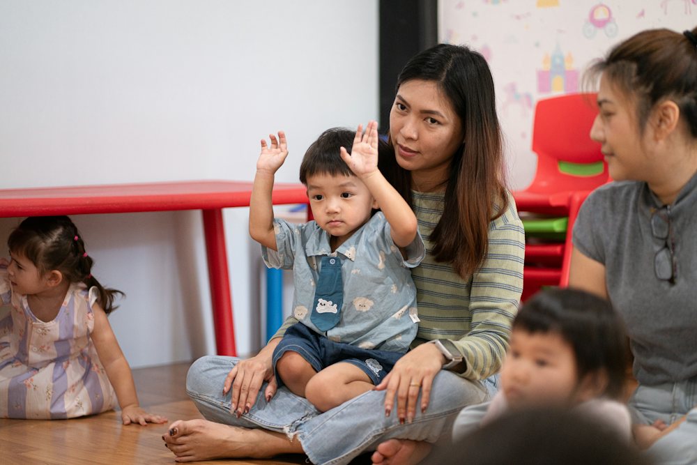 Two teachers sitting on the floor with toddlers